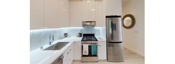 a white kitchen with a stainless steel refrigerator and sink