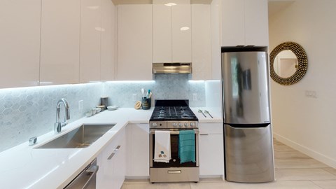 a white kitchen with a stainless steel refrigerator and sink
