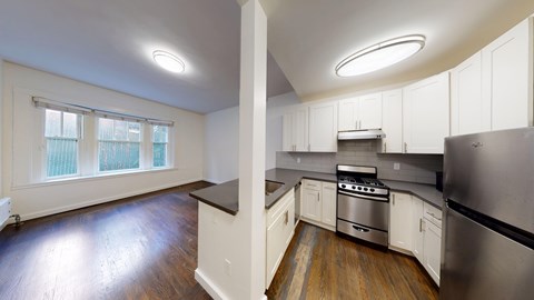 A kitchen with white cabinets and a stainless steel refrigerator.