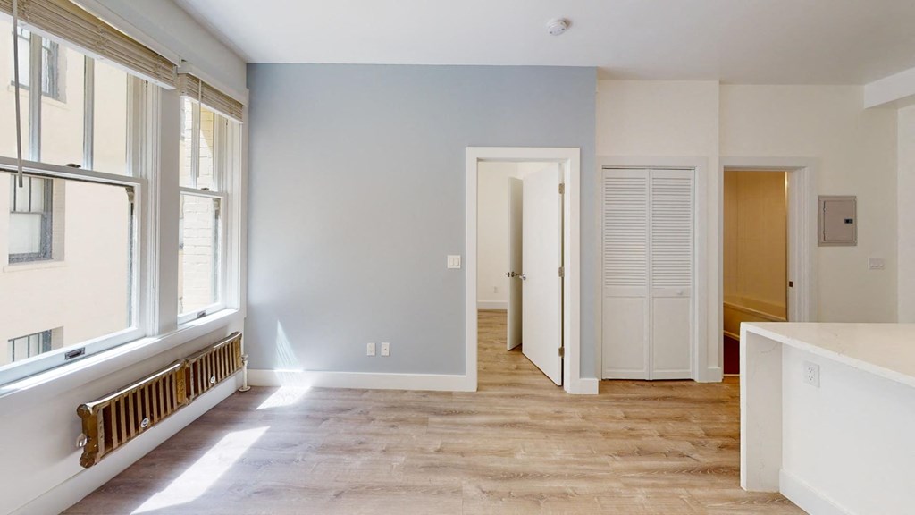 a renovated living room with a large window and a door into a hallway