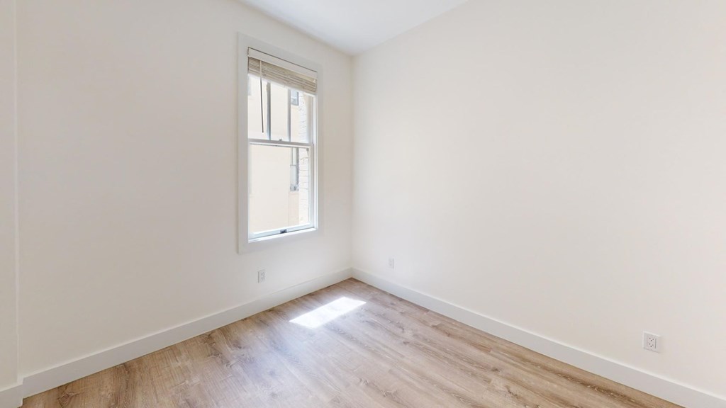 a room with white walls and a window and wooden floors