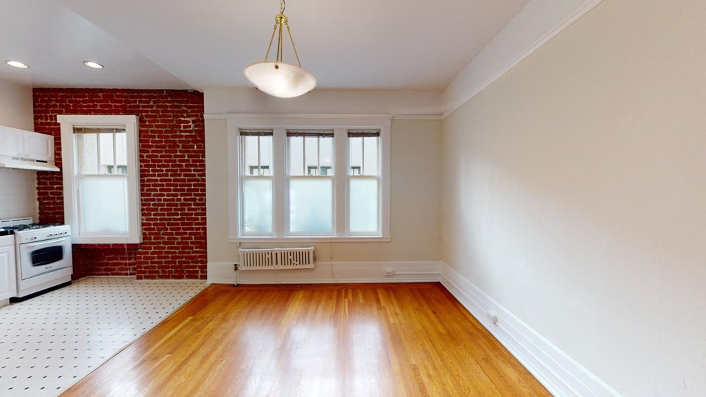 an empty living room with a red brick wall and wood floors