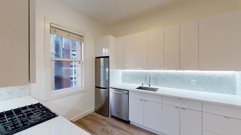 A kitchen with white cabinets and a black stove top.
