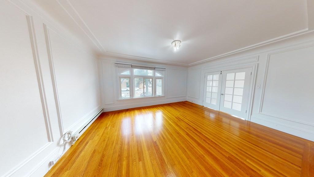a living room with wood floors and white walls and a window