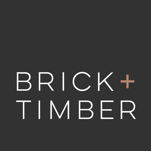 Logo of "Brick + Timber" a property management company in San Francisco, CA, displayed on a dark gray background. The "+" symbol is highlighted in a copper tone.