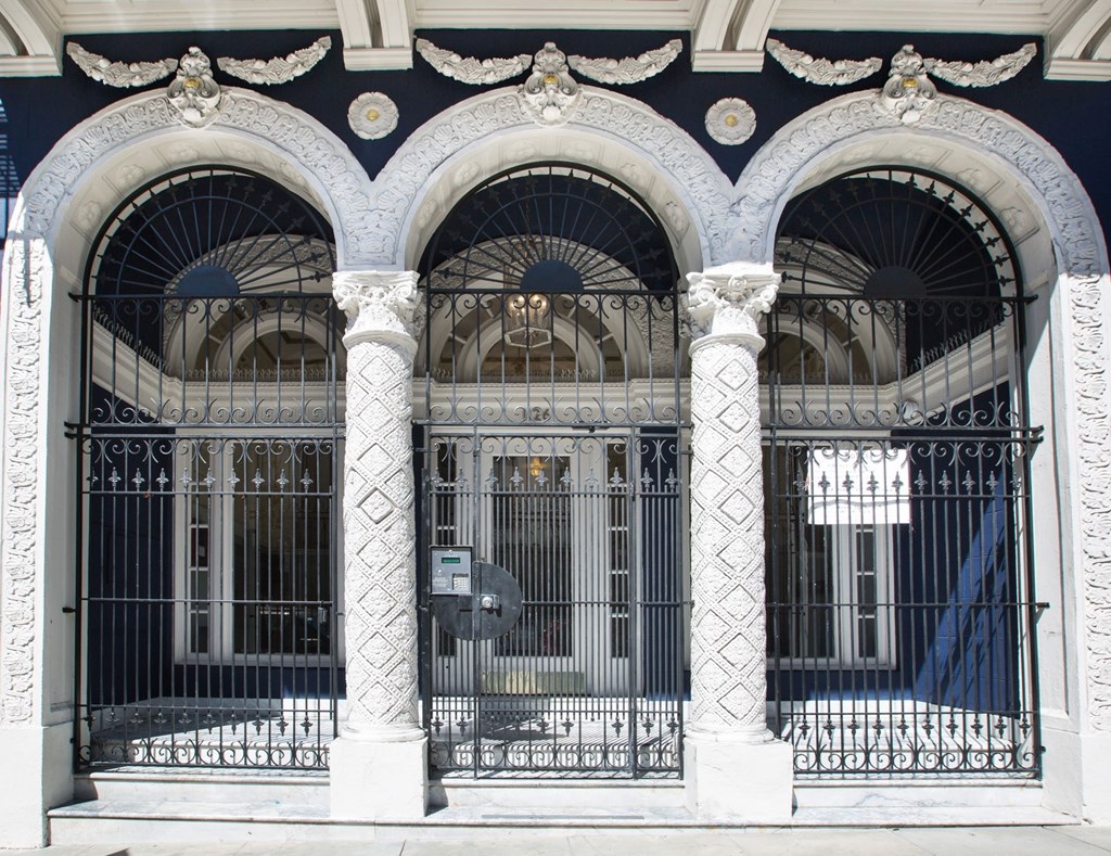 A black and white building with arched windows and a gate.