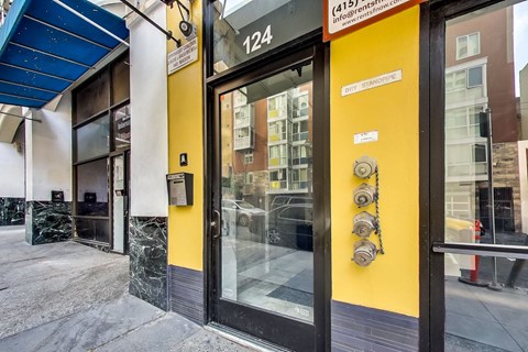 The image shows the front of a building with a yellow wall and a glass door.