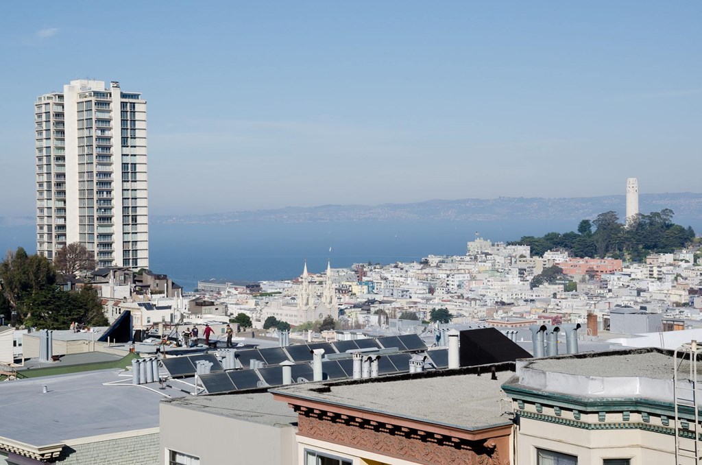 A cityscape with a tall building on the left and a lighthouse in the distance.