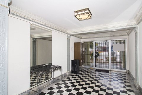 A black and white checkered floor in a room with a white ceiling and a black speaker.