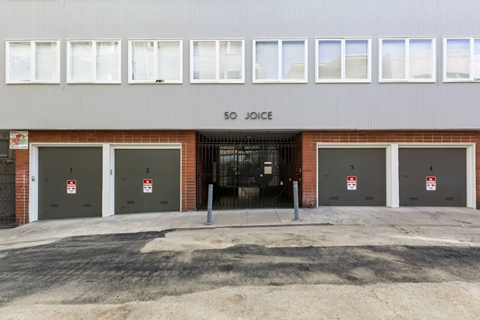 The image shows a building with the name "SO JOICE" on the facade and four doors with red and white signs in front of it.