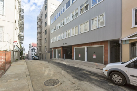 A white car is parked on a street between two buildings.