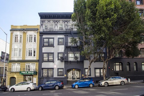 A blue car is parked in front of a building with a sign that says Tina's Salon.
