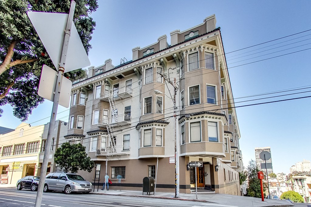 an apartment building on a city street with a car