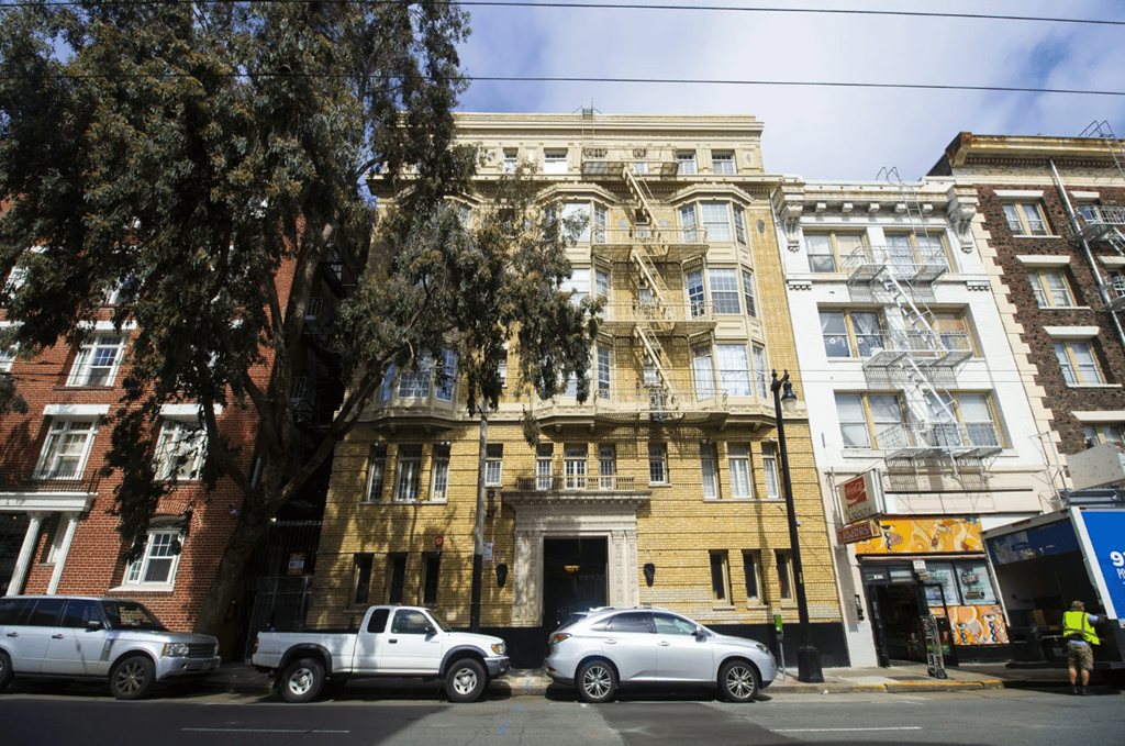 an apartment building on a city street with cars parked in front