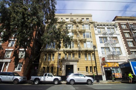 A street view of a row of buildings with cars parked in front.