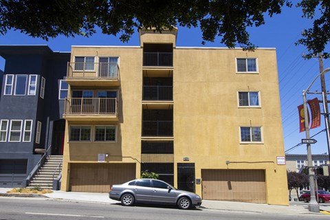 A tan building with a car parked in front.