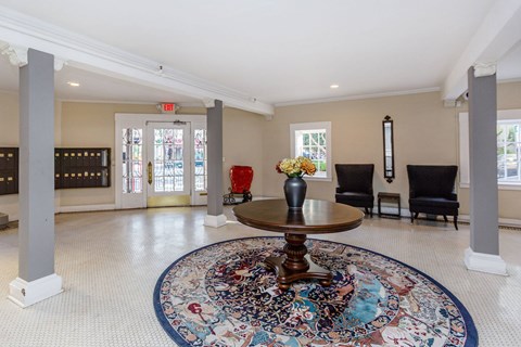 A large, round rug with a multicolored design is placed in the middle of a spacious room with a wooden table and chairs.