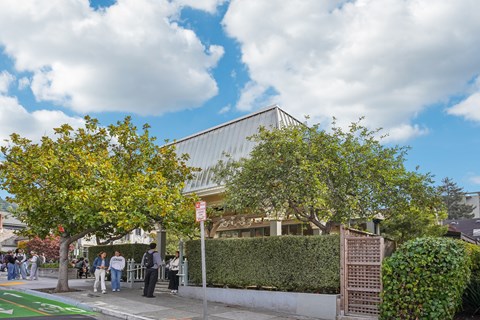 Group of people standing outside of a building with trees