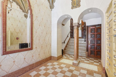 A hallway with a checkered floor and a mirror on the wall.