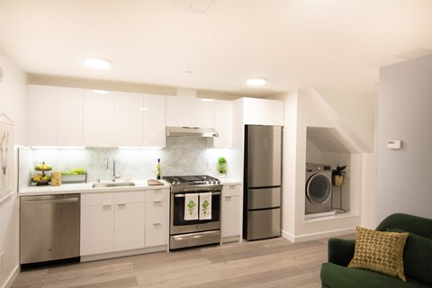a white kitchen with stainless steel appliances and a green couch