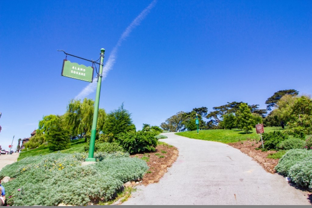 a trail in a park with a green sign and water spraying from a hose