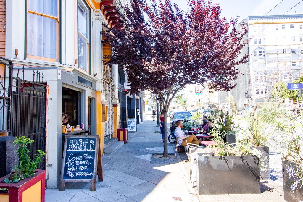 people sitting at tables outside of a sidewalk cafe on a city street