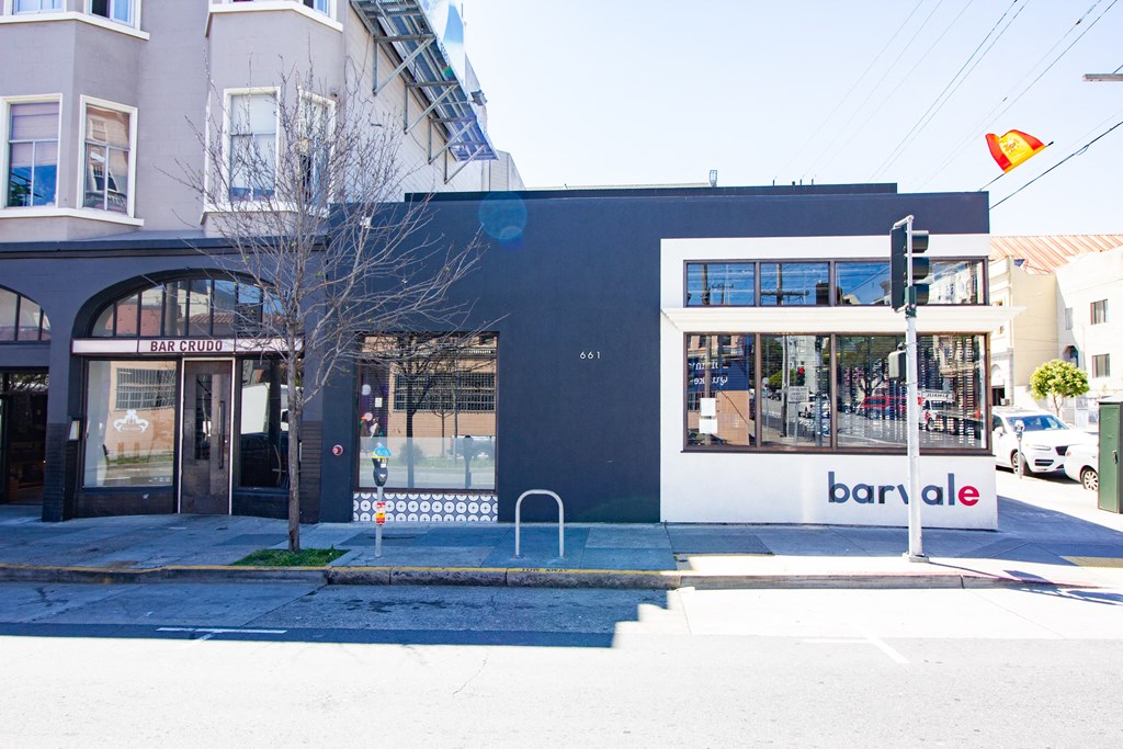 a black and white building with a bar ale storefront on a street