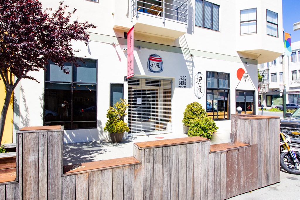 the front of a white building with a wooden fence