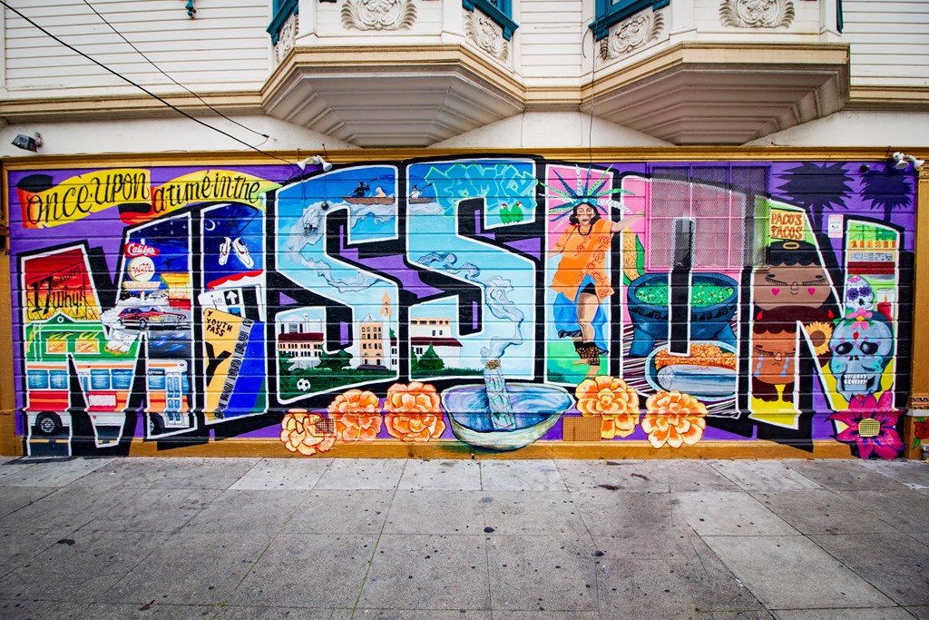 a mural on the side of a building on a sidewalk