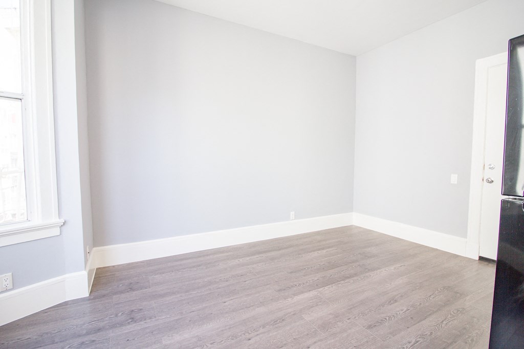 an empty room with wood floors and white walls