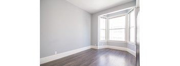 an empty room with wood floors and a window