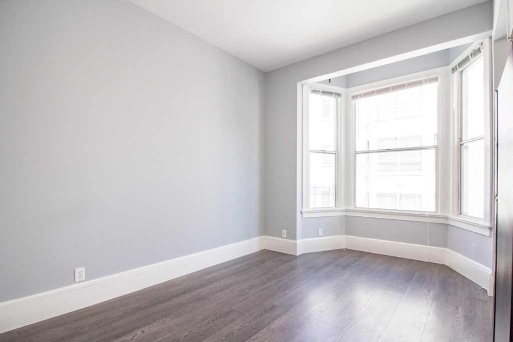 an empty room with wood floors and a window