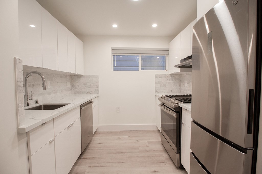 an empty kitchen with stainless steel appliances and white cabinets
