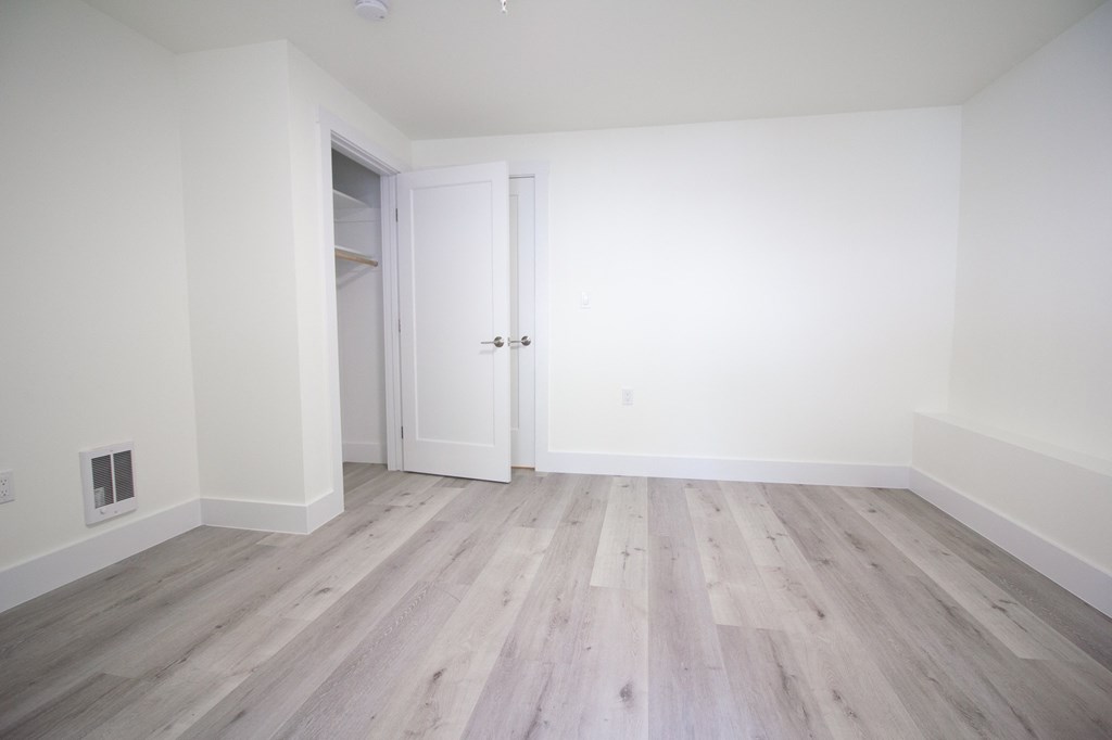 an empty room with wood floors and white walls