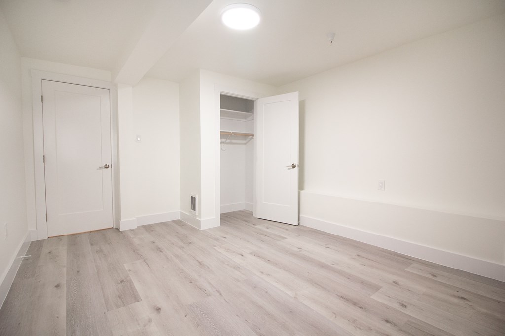 an empty room with white walls and wood flooring