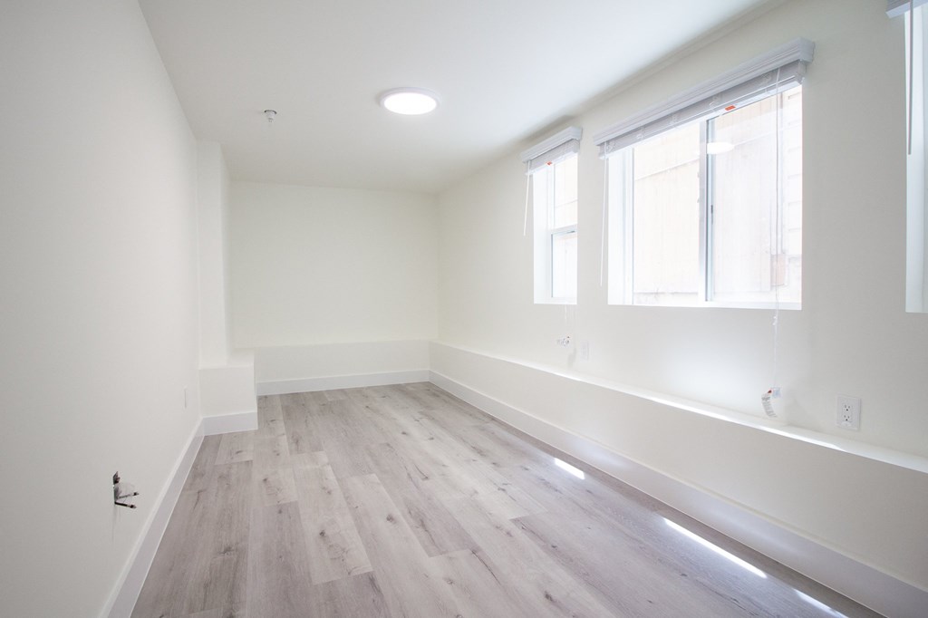 an empty room with white walls and wood floors
