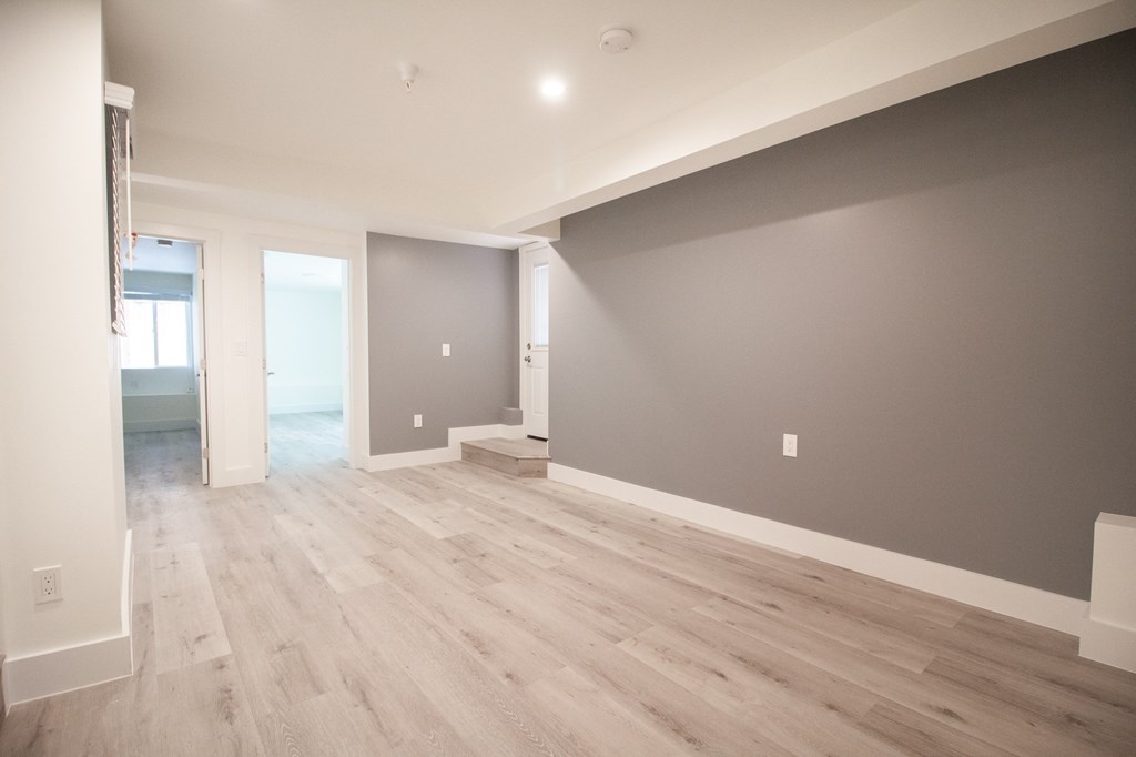 the living room and dining room in a new home with grey walls and wood floors