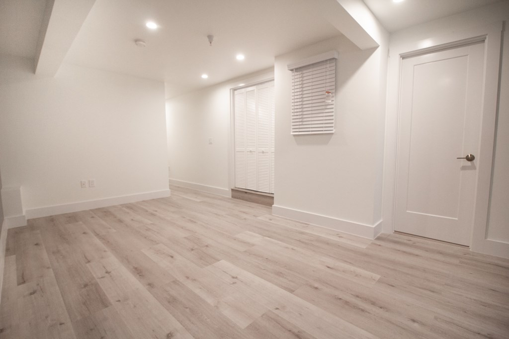 a living room with wood floors and white walls and a door