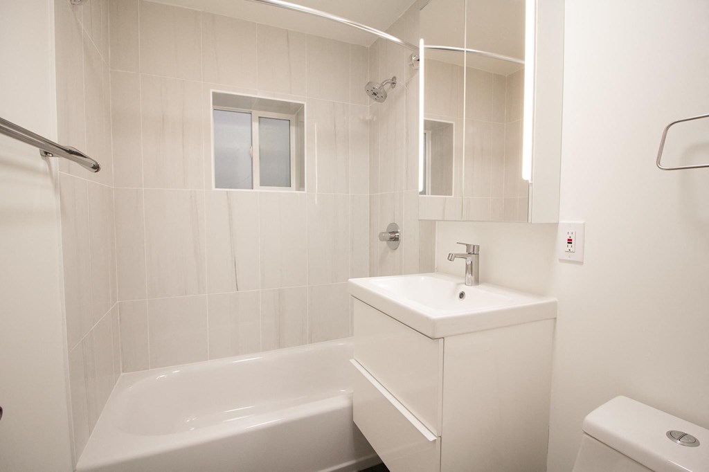 a white bathroom with a sink and a bath tub