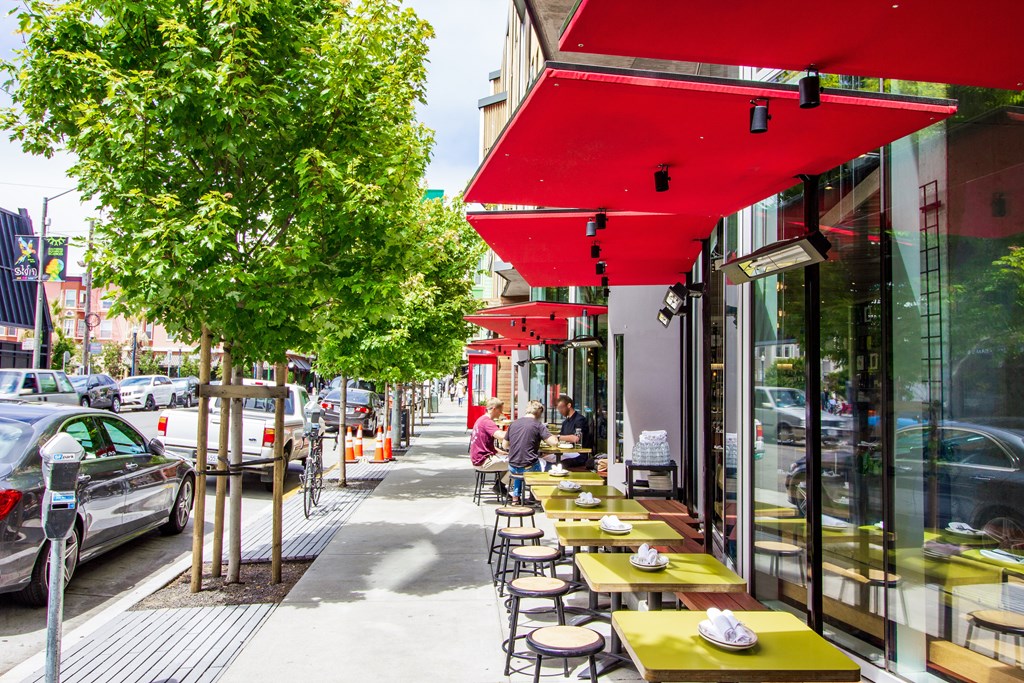 a row of tables and chairs outside of a restaurant on a sidewalk