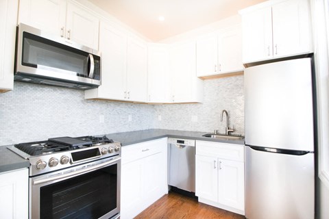 a kitchen with white cabinets and stainless steel appliances