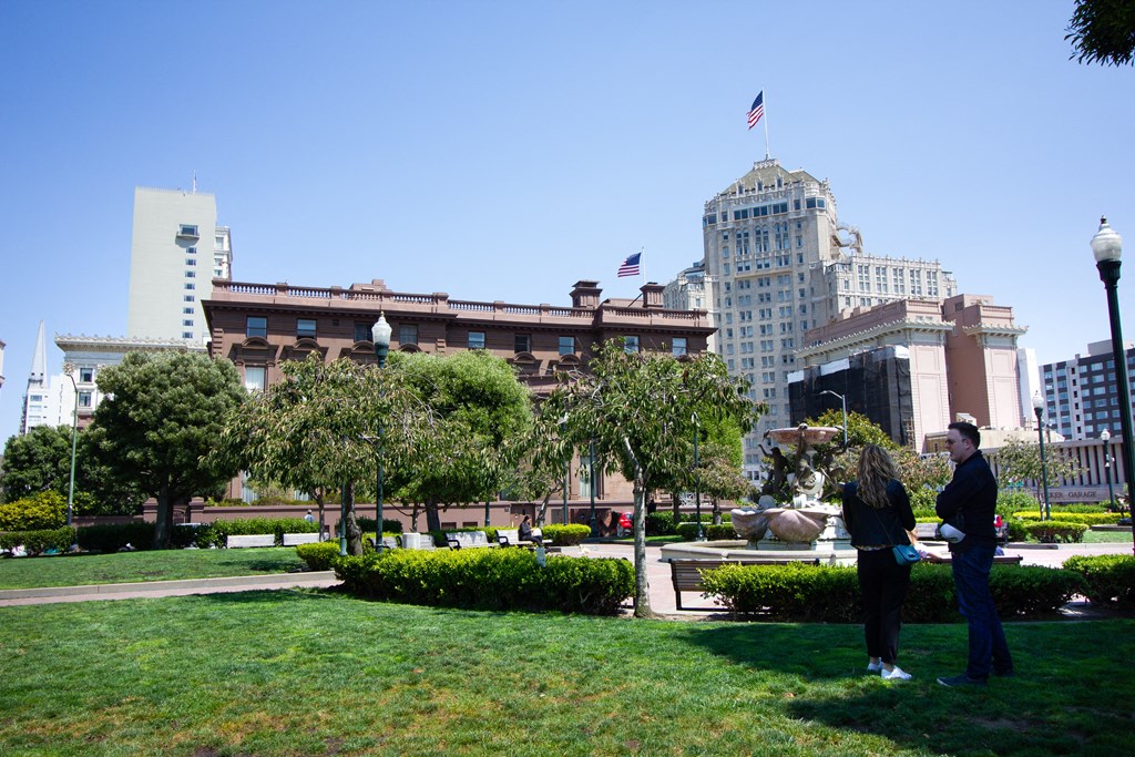 two people standing in a park in front of a city