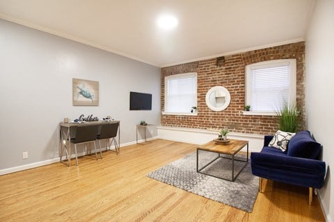an open living room with a brick wall and a desk with a chair