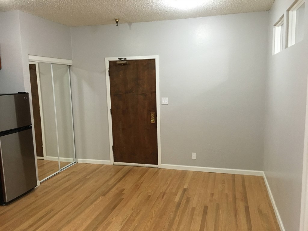 an empty living room with a wooden floor and a door