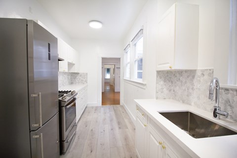 a white kitchen with stainless steel appliances and white counter tops