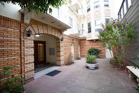 the entrance to a brick building with a patio and a potted plant