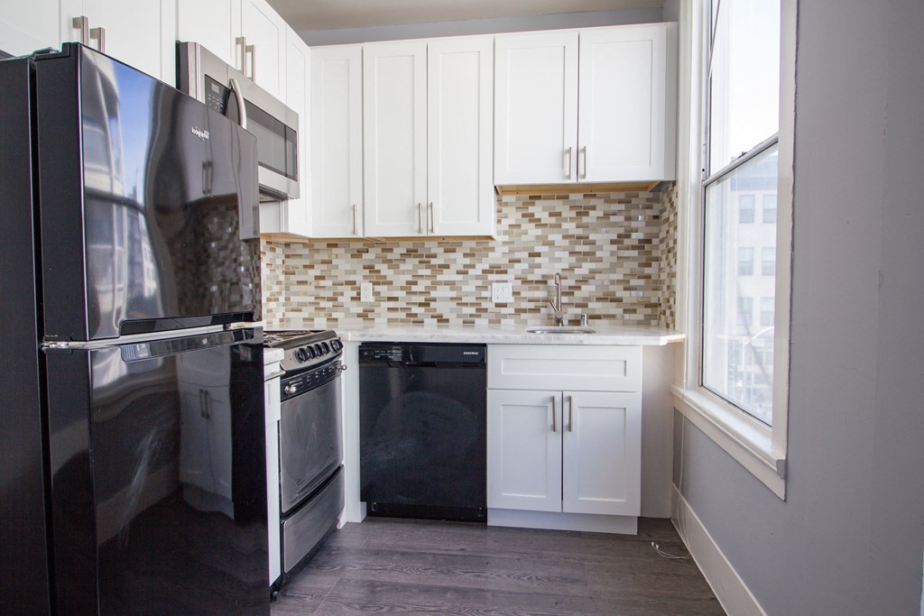 a kitchen with white cabinets and a black refrigerator