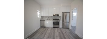 an empty kitchen with white cabinets and stainless steel appliances