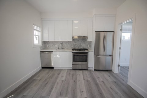 an empty kitchen with white cabinets and stainless steel appliances