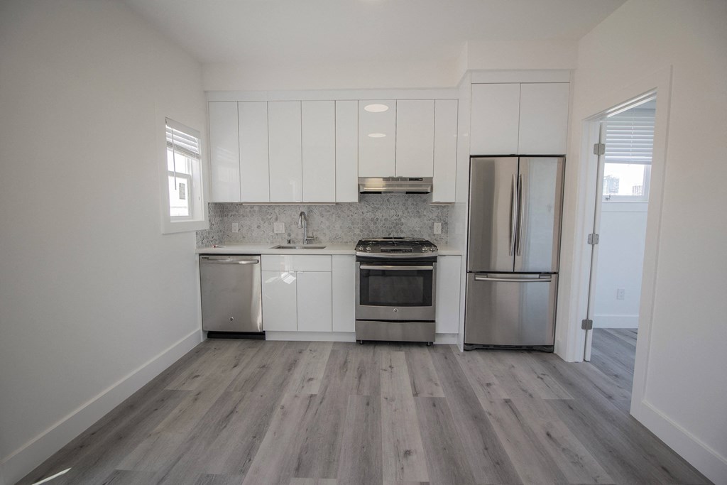 an empty kitchen with white cabinets and stainless steel appliances